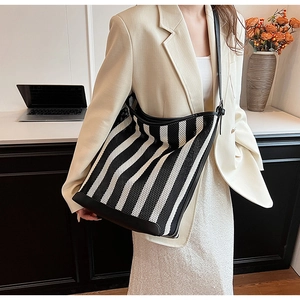 Large black and white striped tote bag with leather trim on model in office