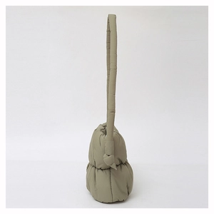 Detail of olive green padded shoulder bag featuring unique cylinder straps and knotted design
