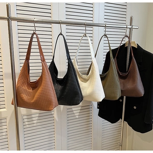 Detail of woven hobo bags in five colors hanging on a rack for daily commute