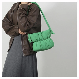 Close-up of bright green quilted puffy cloud bag with knotted handle detail on shoulder