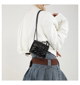 Mini black quilted chain bag shown on model highlighting the elegant small square design