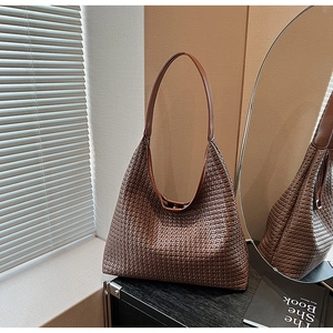 Detail of dark brown woven leather tote with intricate texture and leather strap