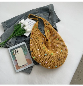 Detail of yellow knit hobo bag with colorful pearl accents and crochet texture
