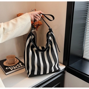 Close-up of black and white striped tote bag with leather straps and knit texture