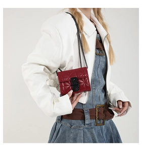 Detail of red quilted mini crossbody bag with black metallic clasp and chain strap
