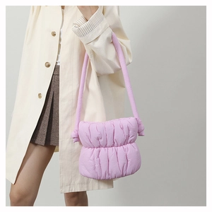 Detailed view of pink quilted puffer shoulder bag with soft cloud texture on model