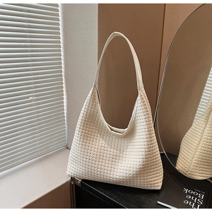 Close-up of woven hobo bag texture and smooth leather strap in a minimalist setting