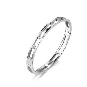Detailed macro view of silver hollowed-out stainless steel bangle with inlaid crystals