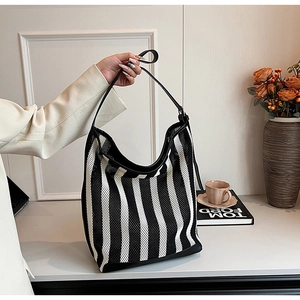 Detail of black and white striped mesh tote with black leather straps and texture