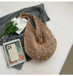 Close-up of a woven beach bag with multi-colored pearls and trendy hollow-out design
