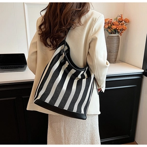 Detail of a large black and white striped tote bag showing woven texture and leather trim
