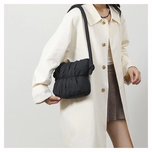 Detail of black quilted shoulder bag with cloud texture and decorative knot strap