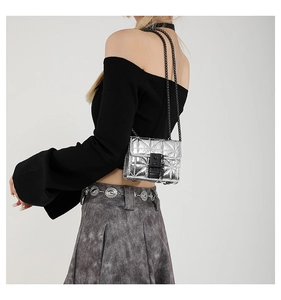 Detail of silver metallic crossbody bag with quilted pattern and black chain strap