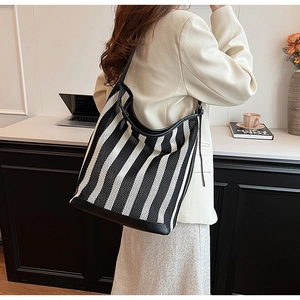 Detail of large striped tote bag with leather straps for daily office commuting