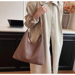 Detail of a large brown woven hobo bag showing intricate leather texture and shoulder strap