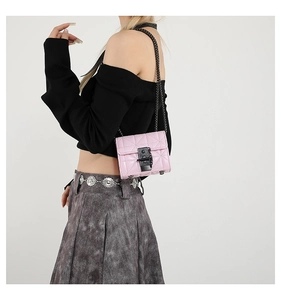 Detail of pink quilted mini bag with black metal chain and turn-lock closure on model