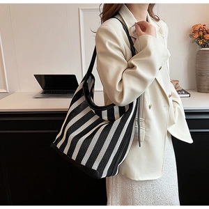 Detailed view of striped woven tote bag with black leather trim and reinforced handles