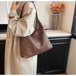 Close-up of dark brown woven tote bag showing detailed texture and long leather strap
