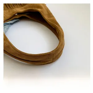 Detail of wide padded handle and blue patterned lining on brown suede tote bag