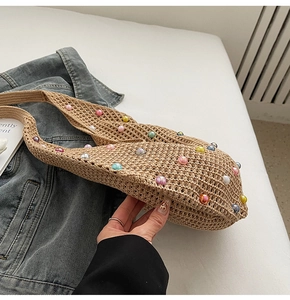 Detail of hand-woven straw shoulder bag with colorful pearls for summer beach wear