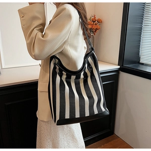 Macro detail of breathable mesh texture and black leather piping on striped tote bag
