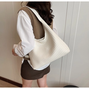 Detail of white woven hobo bag with wide shoulder strap showing texture and capacity