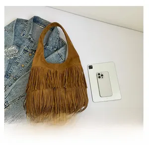 Detail of vintage brown suede hobo bag with long fringes, next to tablet for size scale