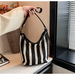 Detail of black and white striped knit mesh shoulder bag with adjustable leather strap