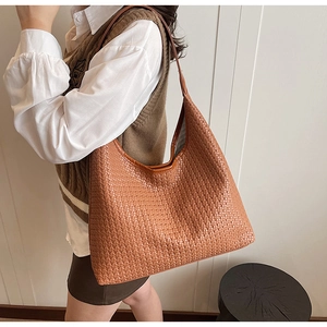 Close-up of a large tan woven hobo shoulder bag featuring intricate textured patterns