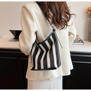 Detail of black and white striped woven tote bag featuring slim leather shoulder straps