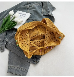 Detailed close-up of yellow knit tote bag featuring colorful bead accents and woven texture