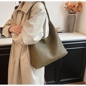 Detail of olive green woven leather hobo bag worn with a chic beige trench coat