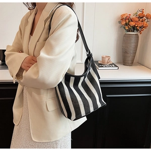 Detail of black and white striped knit hobo bag featuring woven texture and leather strap
