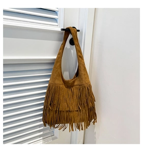 Close-up of brown suede hobo bag featuring decorative long fringes and retro boho design