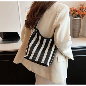 Detailed close-up of a black and white striped knit mesh shoulder bag on a model
