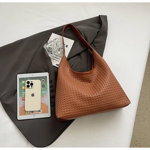 Detail of the intricate brown woven texture and wide strap of the large hobo tote bag