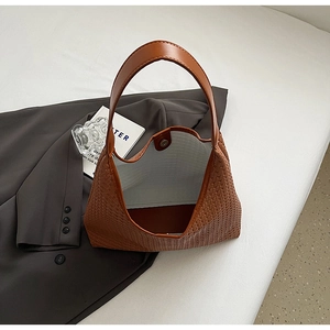 Detail of brown woven hobo bag featuring wide leather strap and magnetic closure