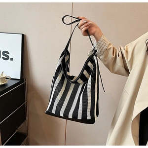 Detail of black and white striped mesh tote bag with leather trim and knotted side design