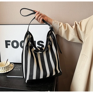 Detail of striped mesh tote bag with black leather shoulder straps and reinforced corners