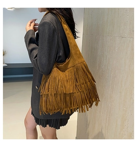 Detailed view of brown suede shoulder bag featuring long fringe tassels in boho style