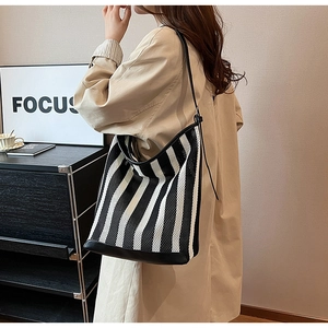 Detail of striped woven tote bag with mesh texture and premium leather bottom