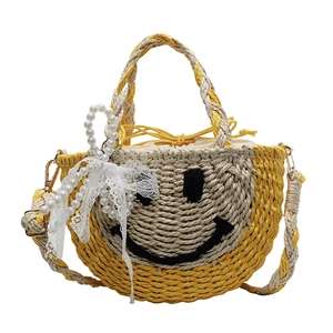 Handmade woven straw beach bag with a yellow smiley face design and pearl lace bow
