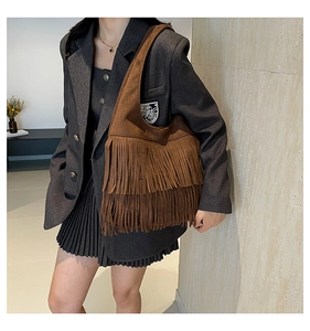 Detailed view of bohemian dark brown suede fringe shoulder bag worn by a model