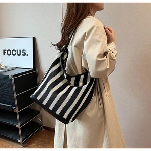 Close-up of black and white striped knit tote bag with black leather shoulder straps