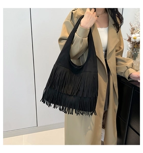 Detail of black faux suede hobo bag featuring double-layered fringe tassels and shoulder strap