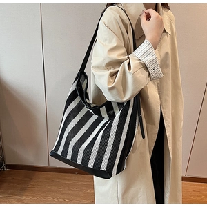 Detail of black and white striped mesh tote bag with reinforced base on a model shoulder