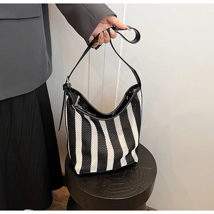 Detail of striped mesh shoulder bag with black leather strap and metal buckle fastener