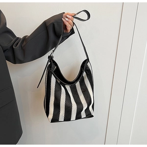 Close-up of black and white striped mesh knit hobo bag with adjustable leather shoulder strap