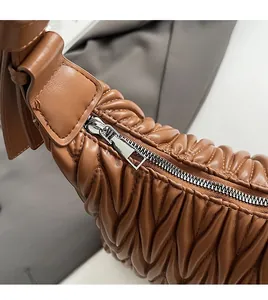 Close-up of smooth metal zipper detail on brown quilted leather dumpling bag