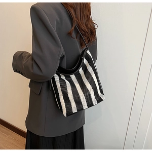 Detail of striped mesh tote bag featuring woven texture and black leather shoulder strap